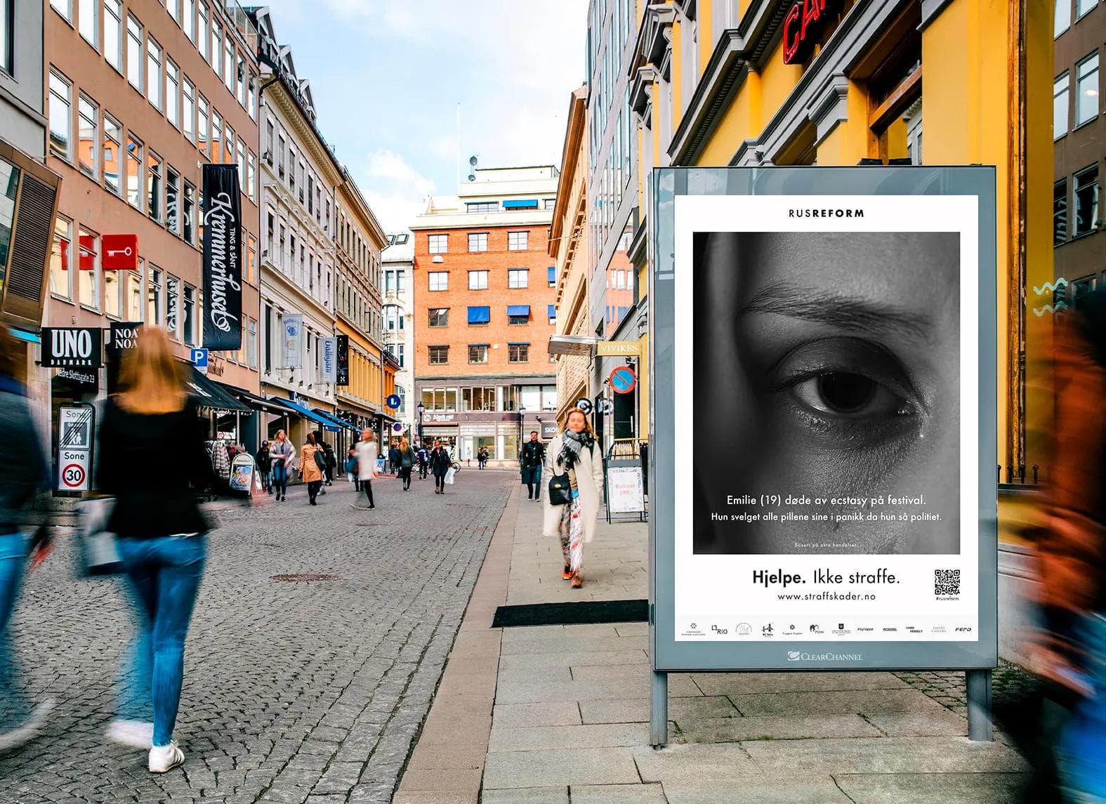 Outdoor Clear Channel display showing the Emilie campaign poster on a busy pedestrian street.