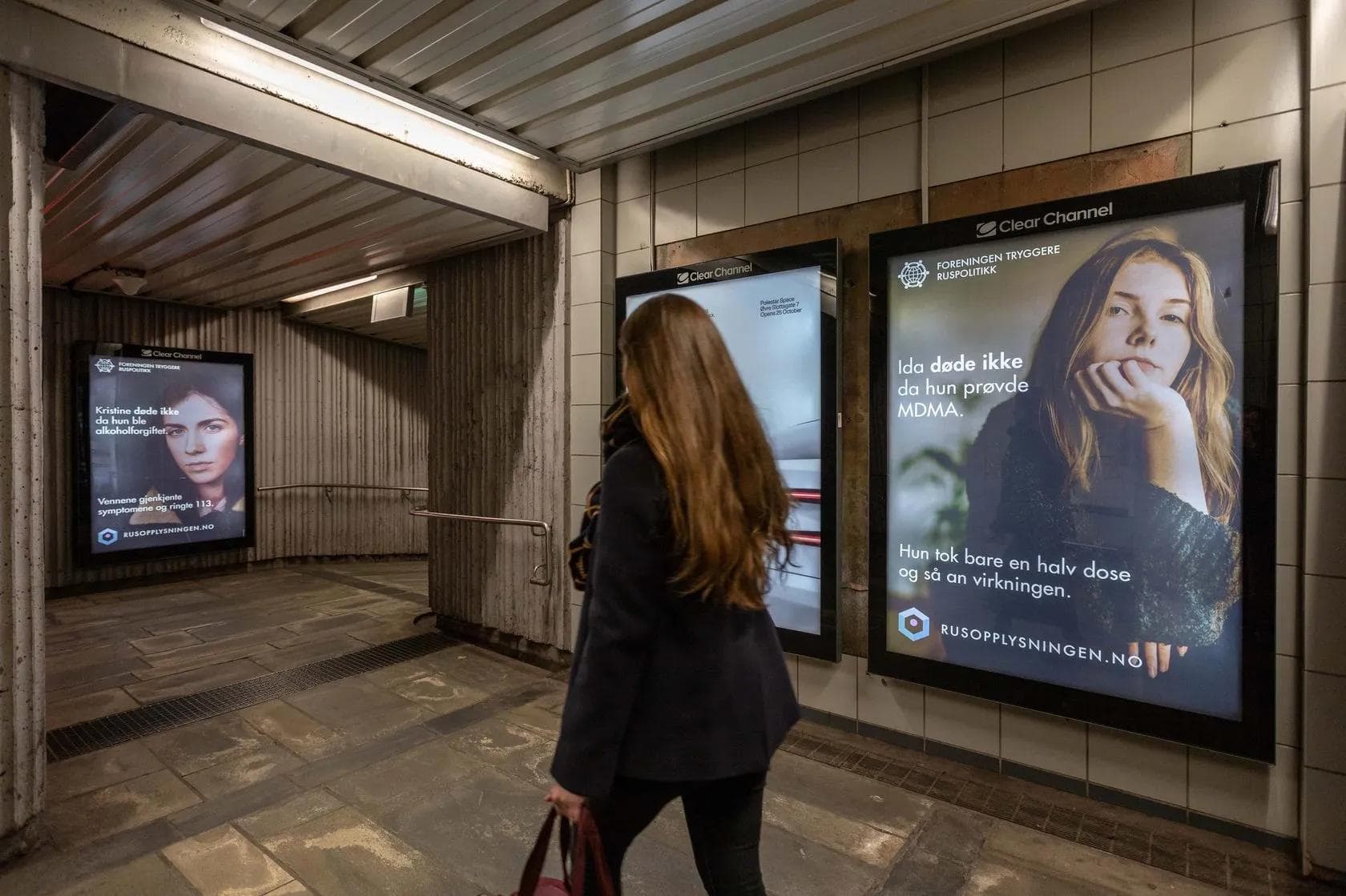 Three backlit campaign posters in an underground pedestrian tunnel — Rusopplysningen harm reduction messages.