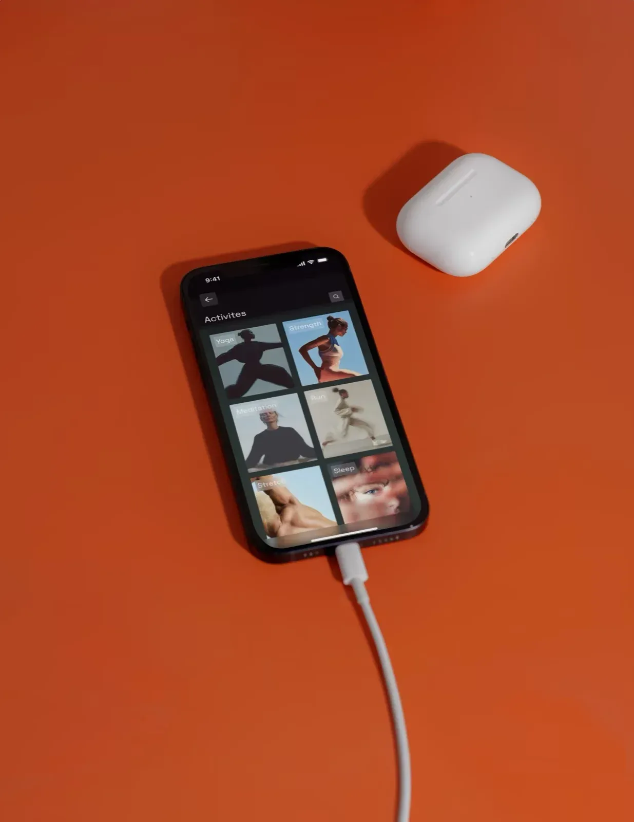 The Endor app library on a phone beside AirPods on a bright orange background.
