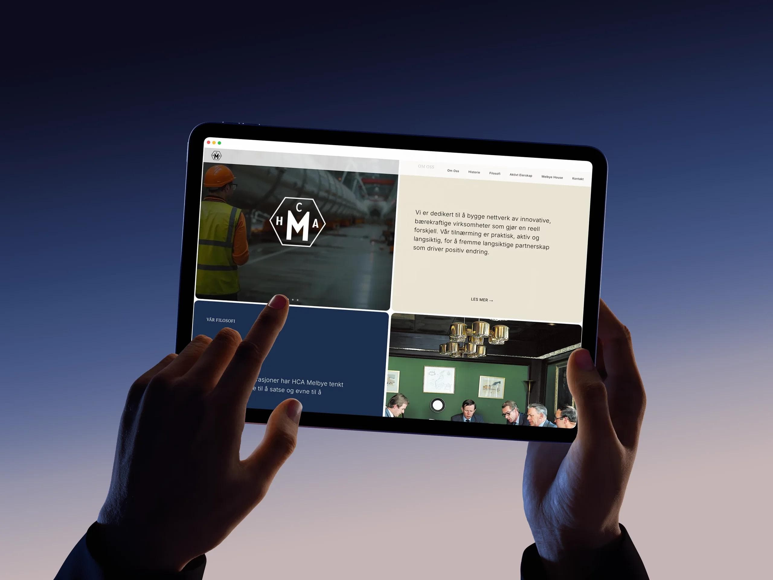 H.C.A Melbye website homepage on a tablet, held up against a blue evening sky